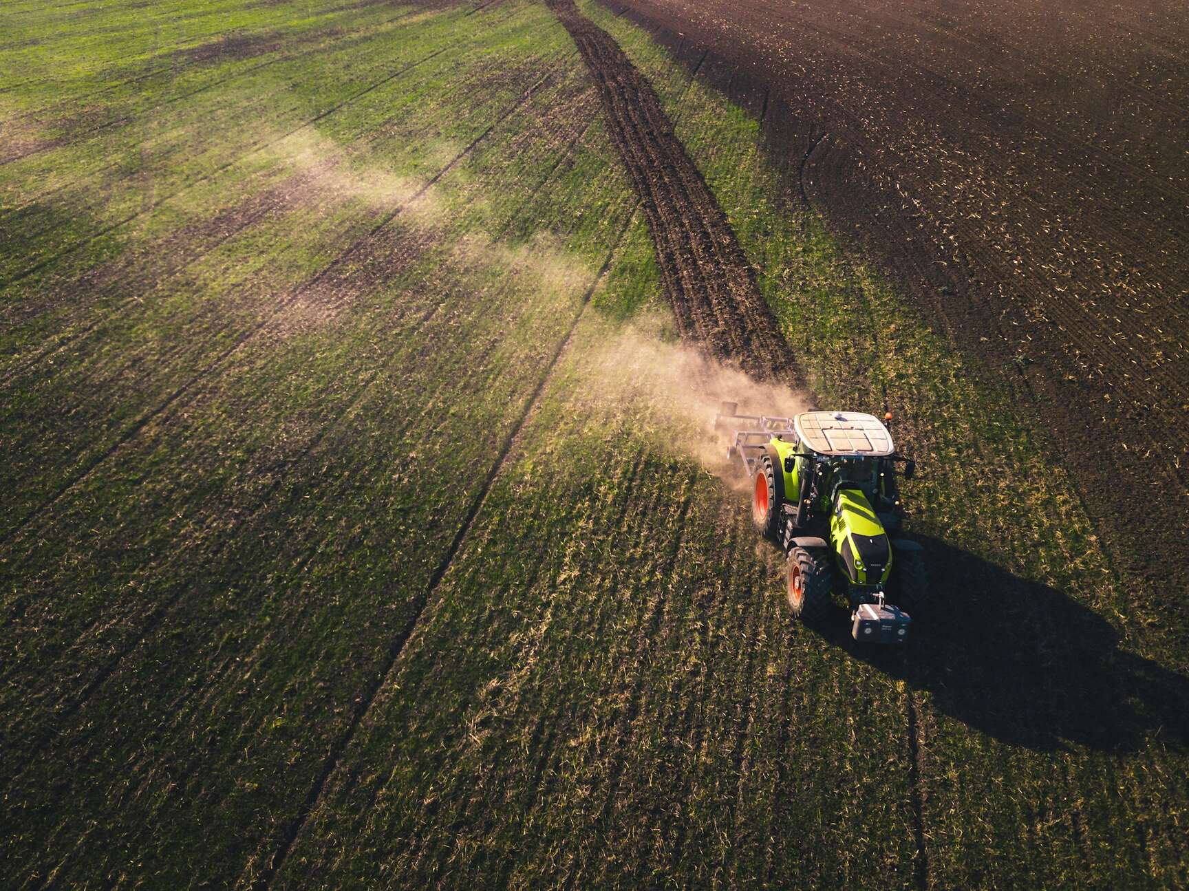 Green and white tractor on green grass field during daytime